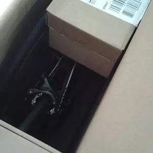 Ein teilweise verpacktes Fahrrad ist in einem großen, offenen Versandkarton sichtbar.