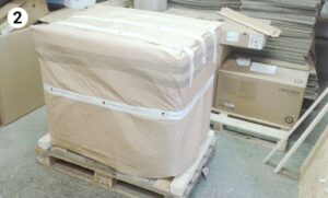 Großer Gegenstand in braunes Papier eingewickelt und sicher auf einer Palette verzurrt.